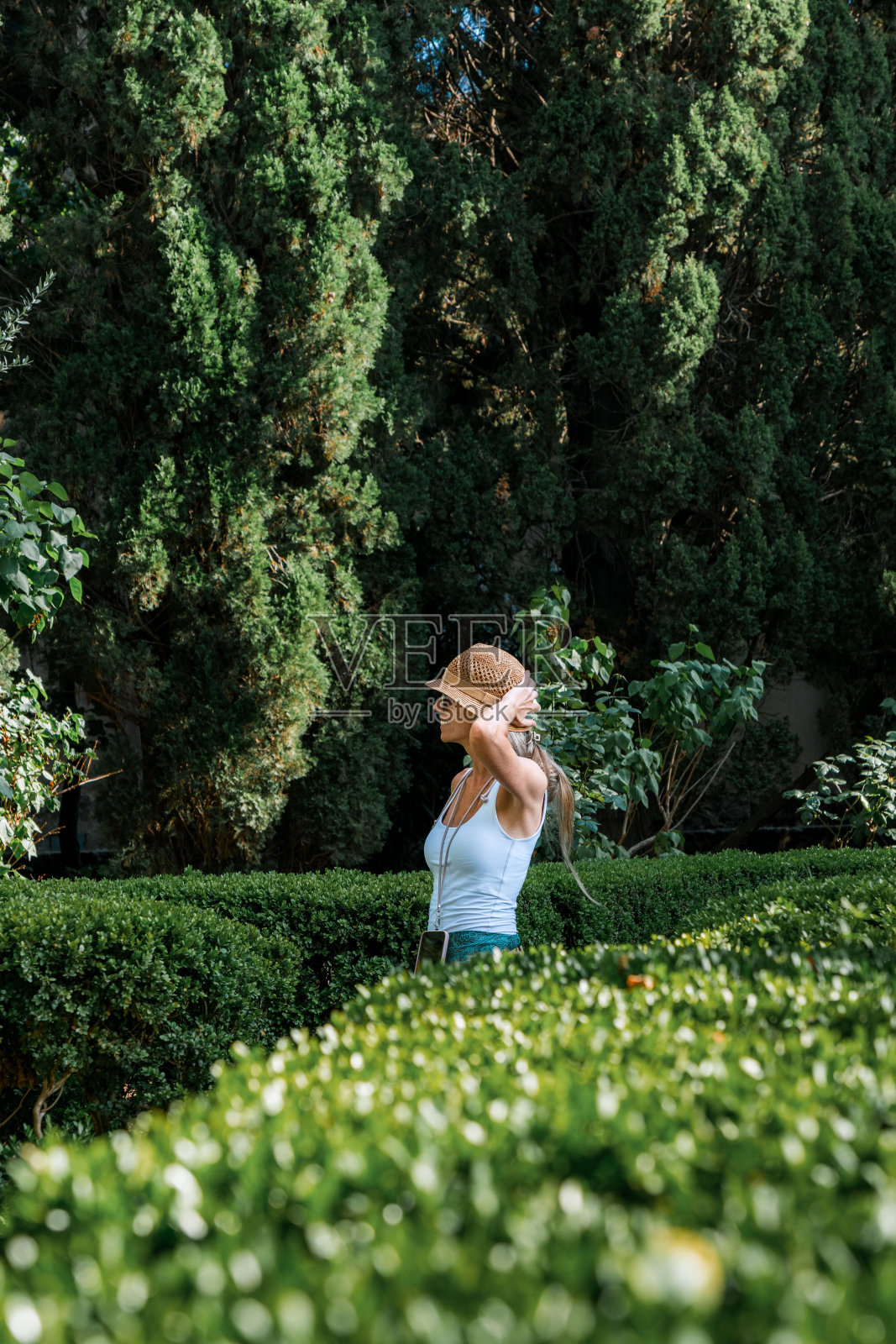 戴着帽子微笑的金发女人走在公园中央照片摄影图片