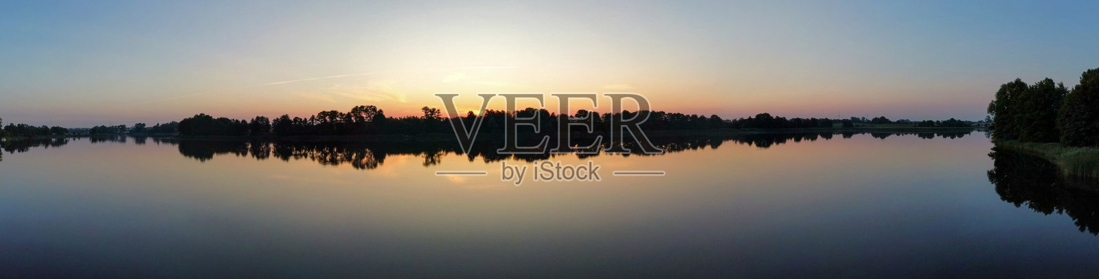 清晨的夕阳映在森林里的湖面上。海岸上的芦苇。阳光。从无人机上看。照片摄影图片