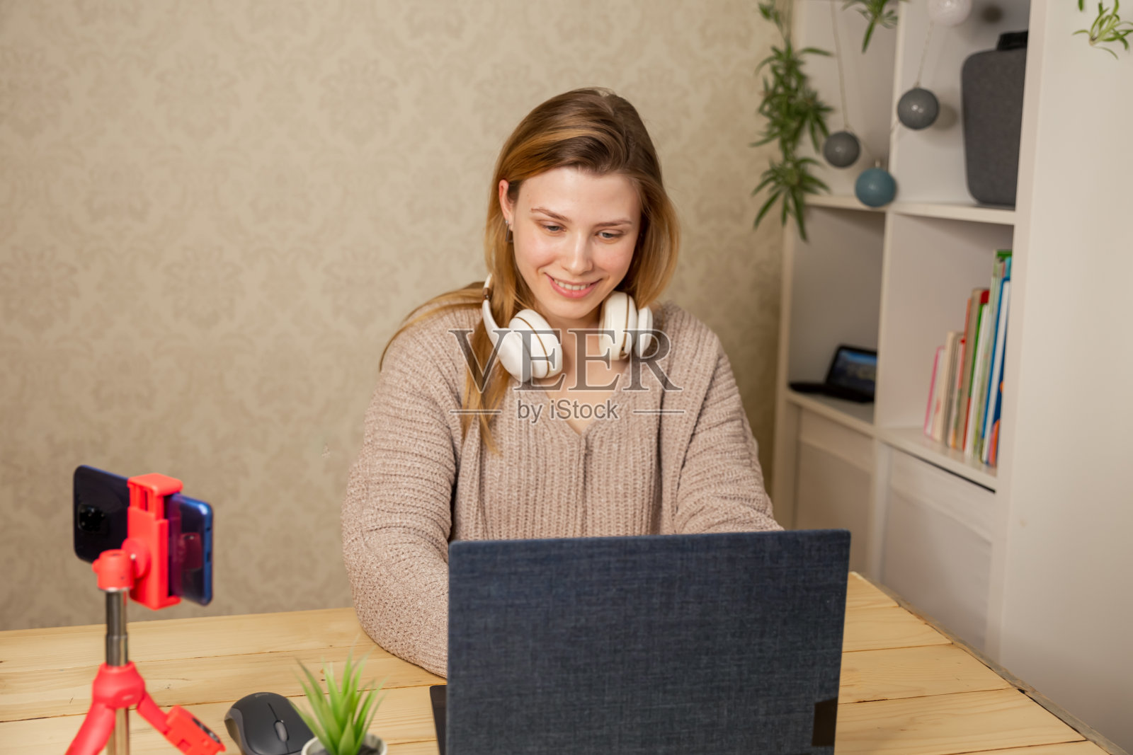 女孩坐在三脚架上的手机摄像头前录制教学视频照片摄影图片