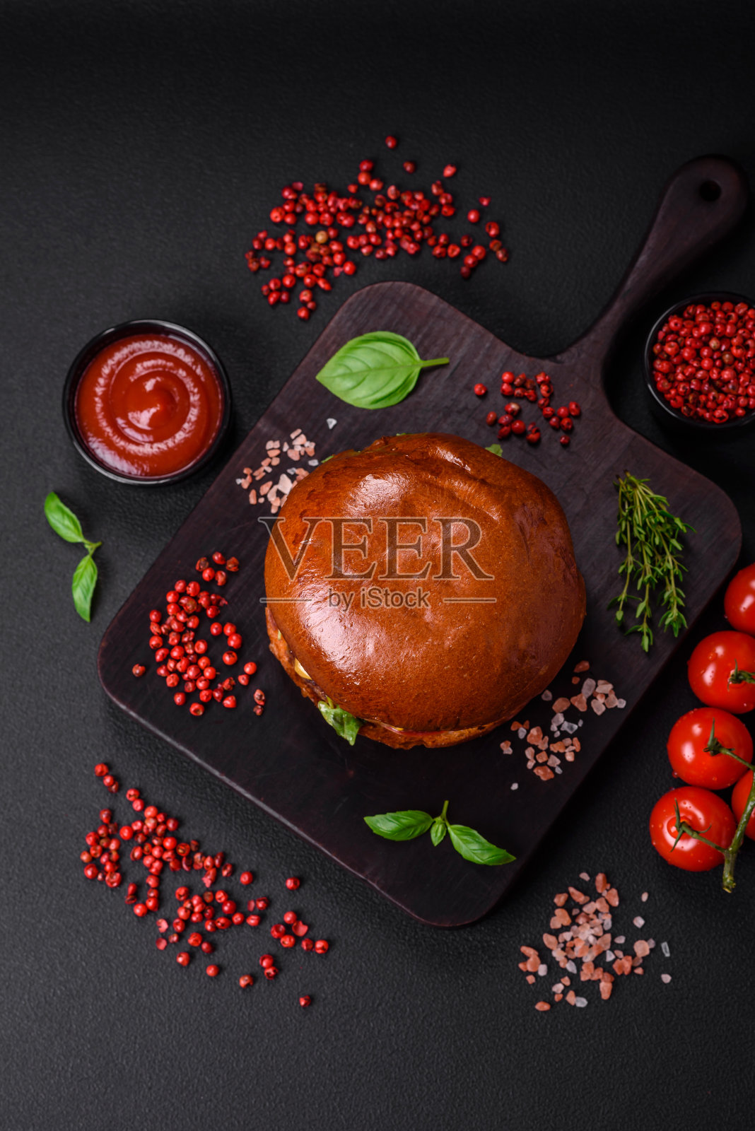 汉堡配多汁牛肉排,奶酪,西红柿,盐,香料和香草照片摄影图片