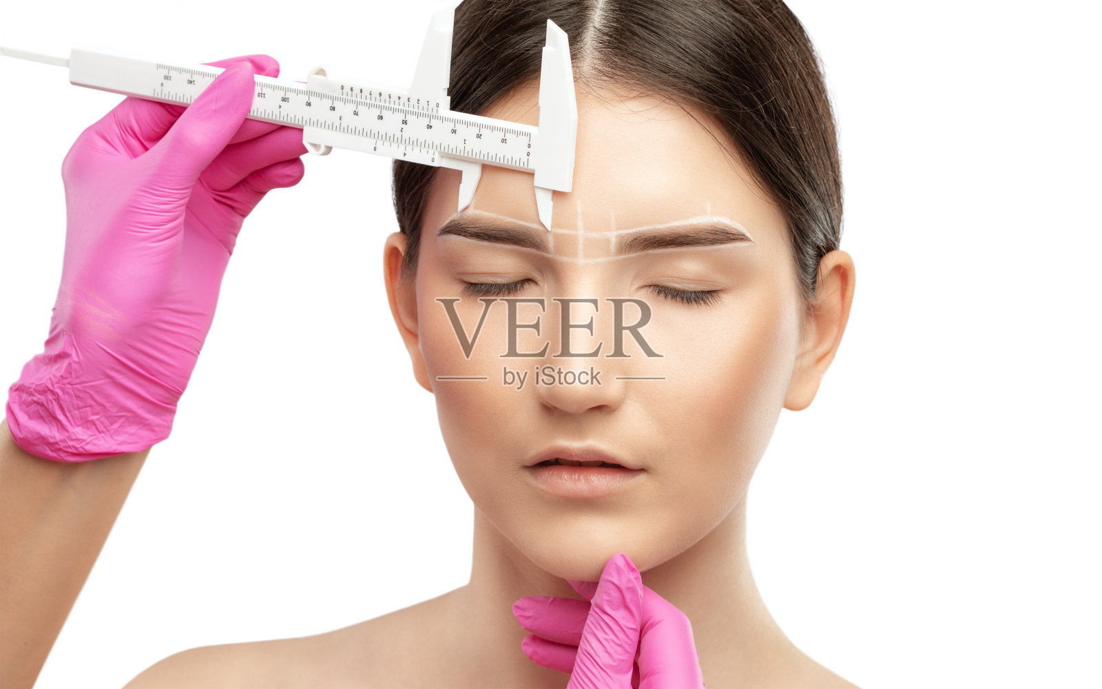 化妆师用白色铅笔在眉毛上做记号,然后画眉毛。专业的化妆和面部护理。照片摄影图片