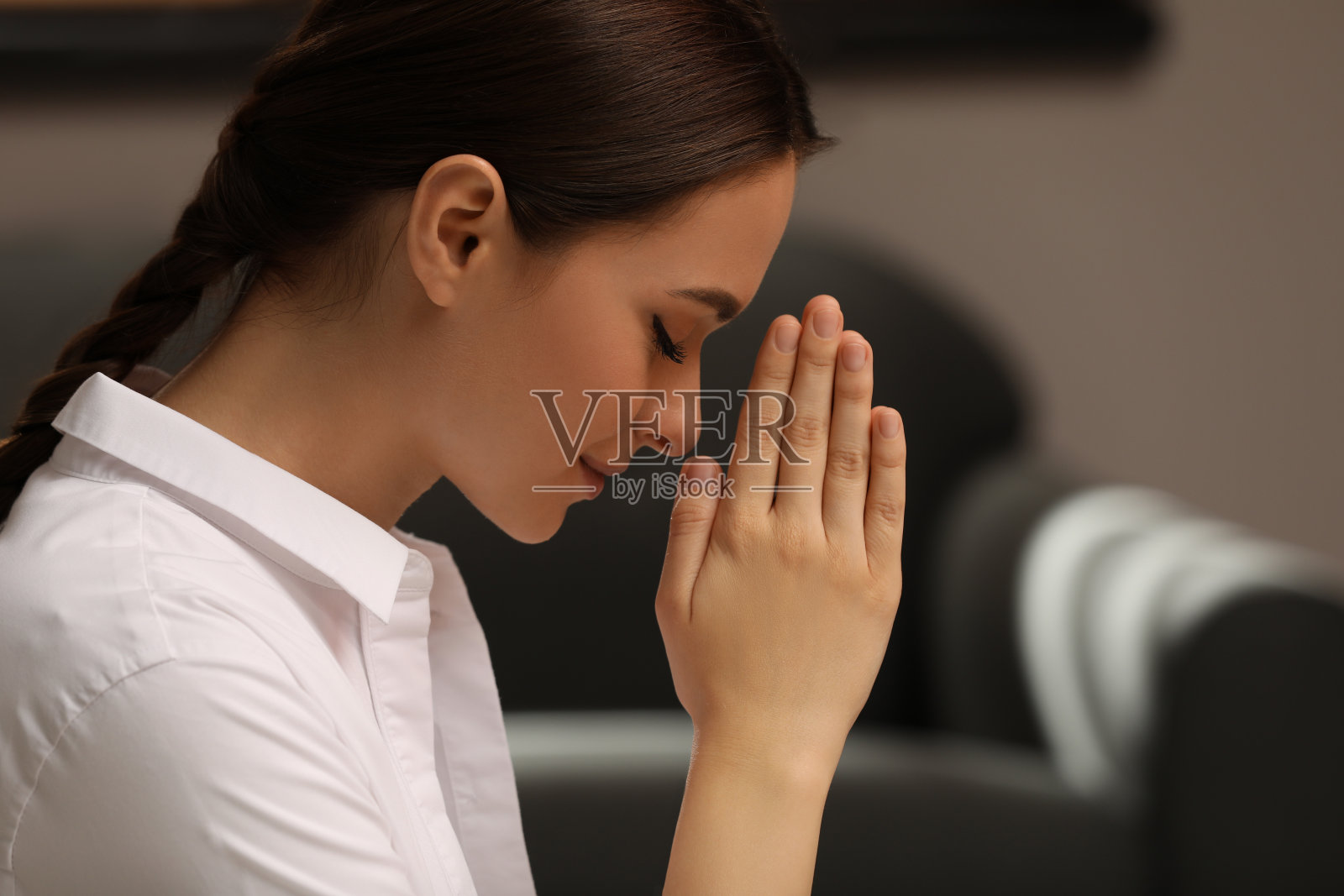 虔诚的年轻女子紧握双手在室内祈祷照片摄影图片