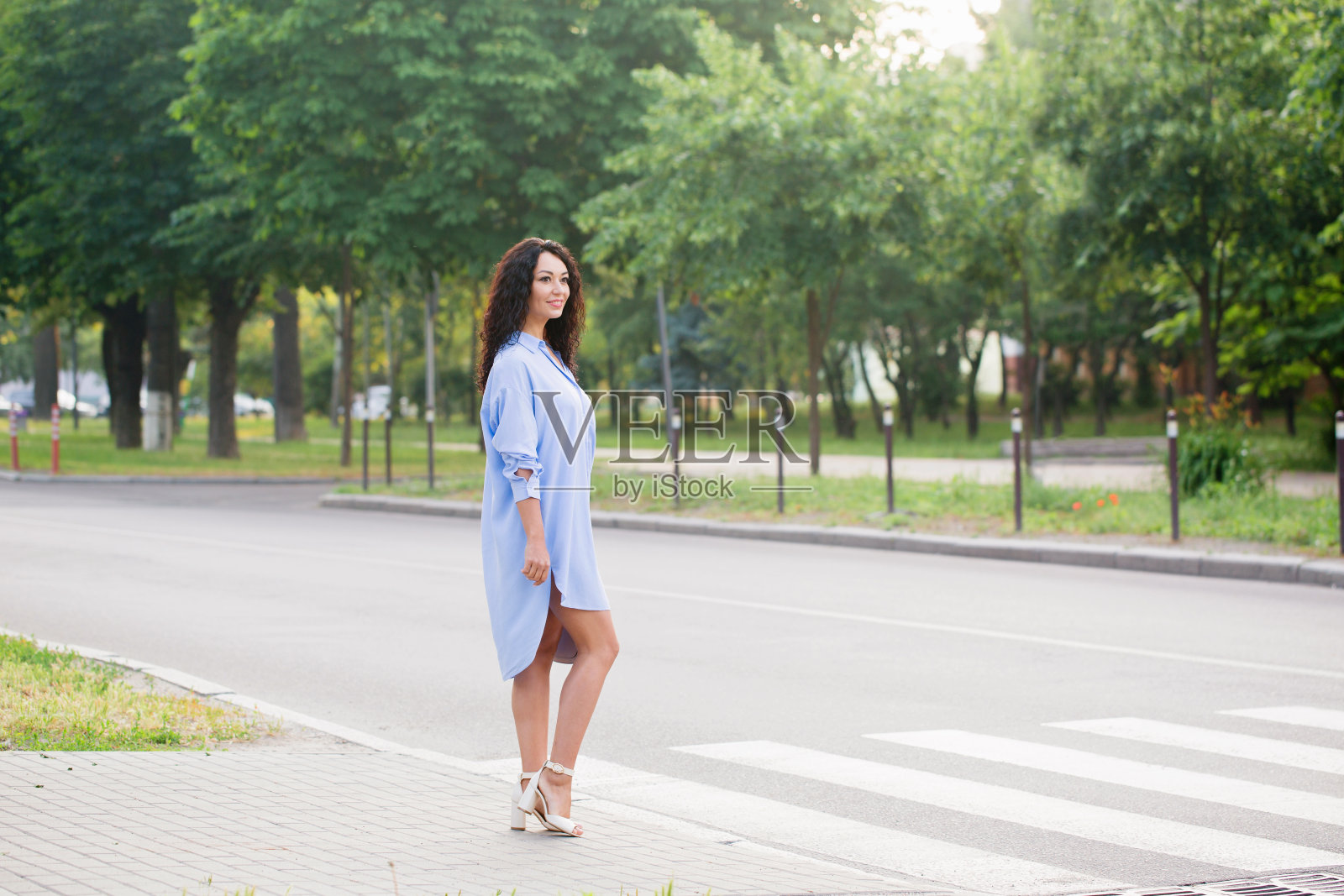 一位穿着蓝色长衬衫的漂亮女商人穿过马路照片摄影图片