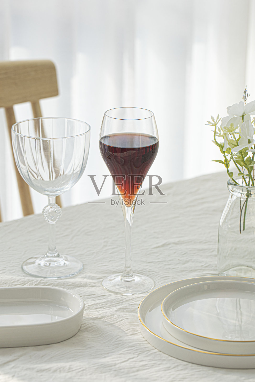 白桌子上的酒杯和白盘子。照片摄影图片
