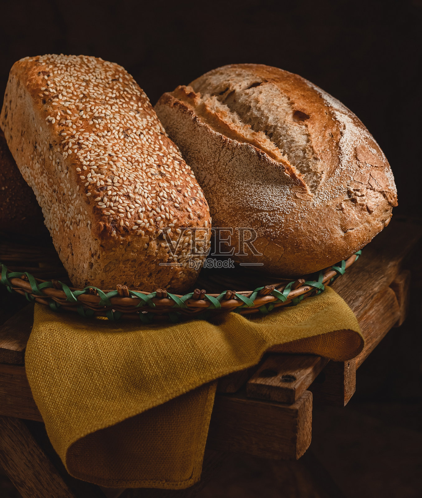 全谷物面包放在篮子里。芝麻面包和黑麦面包的黑色乡村背景。健康的烤面包。照片摄影图片