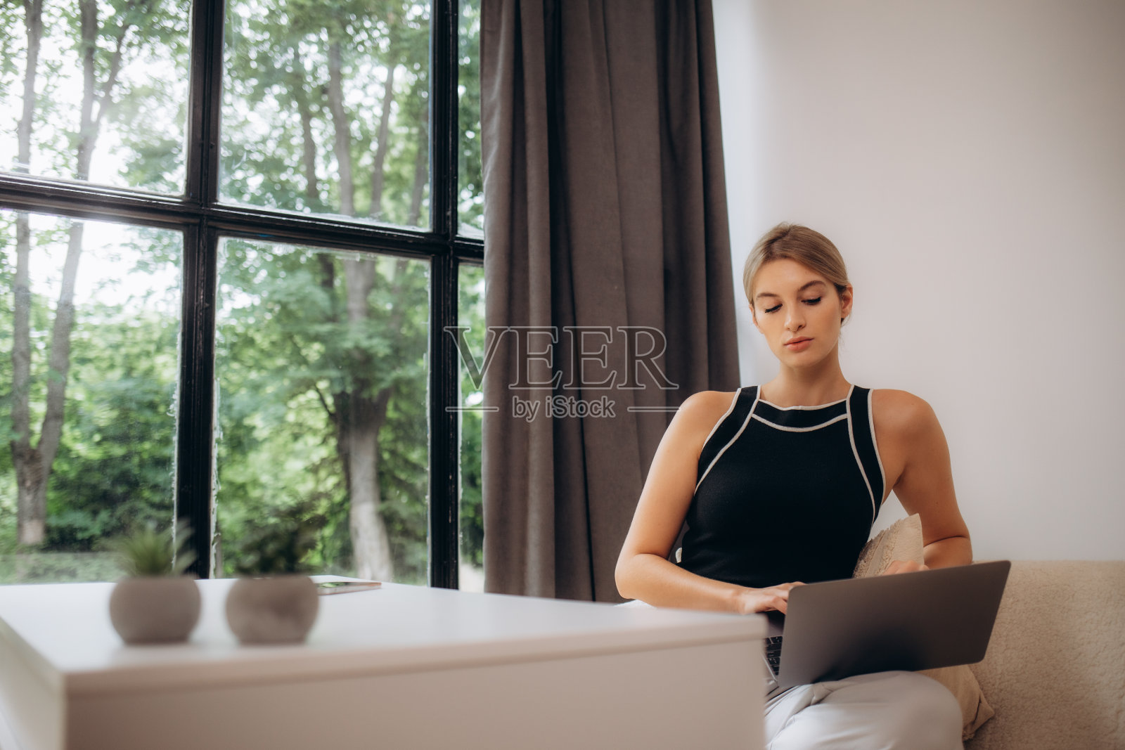 年轻漂亮的女文案在她宽敞明亮的办公室里用电脑键盘打字和写博客。忙碌的女人在工作照片摄影图片