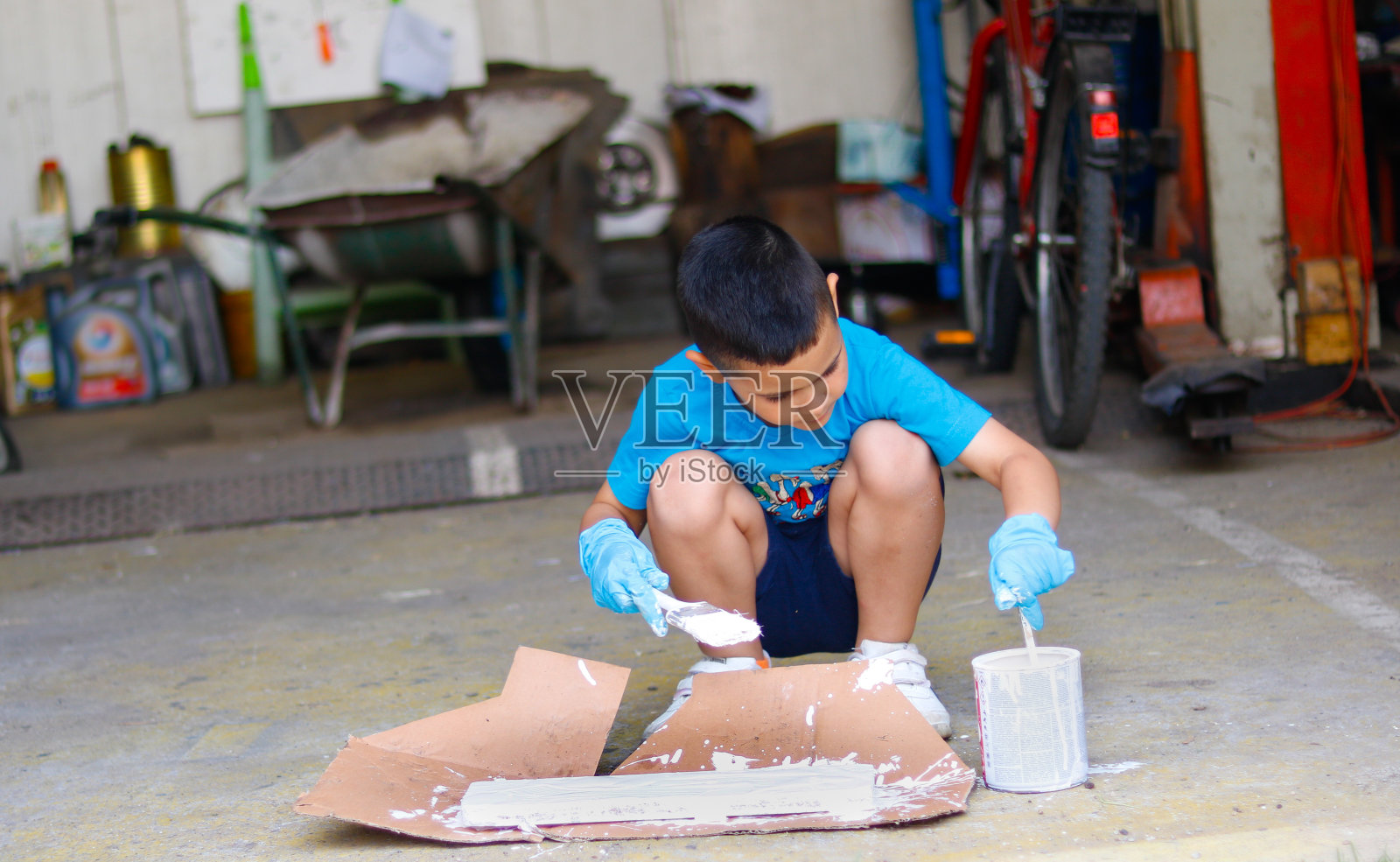 男孩在车库里帮助父亲粉刷照片摄影图片