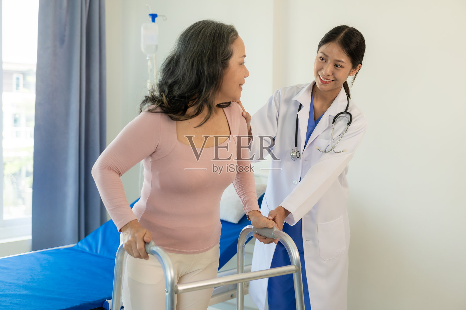 亚洲老年妇女在护士的支持下进行物理治疗。年轻妇女在疗养院为肩部肌肉进行物理治疗照片摄影图片