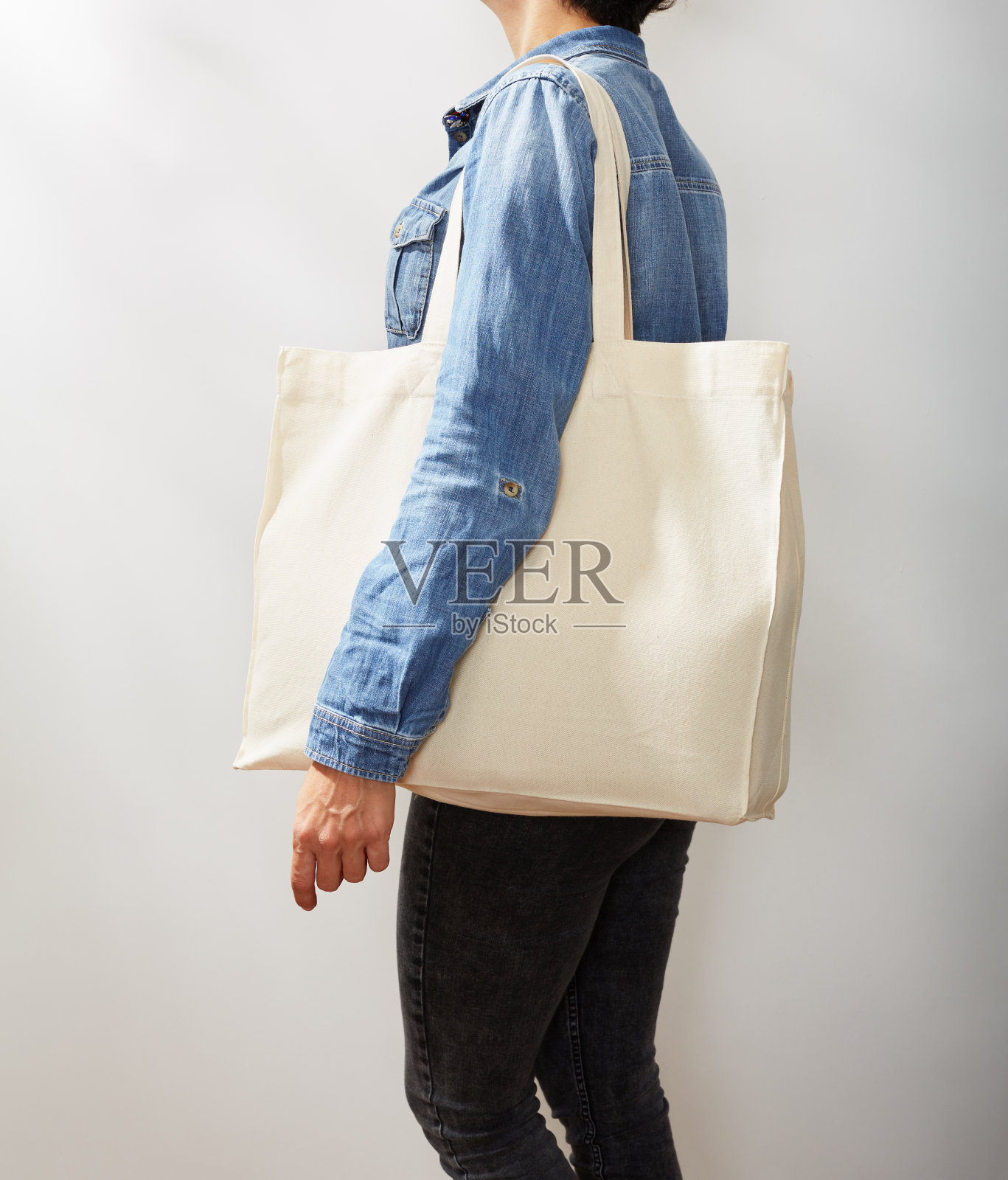 穿着牛仔衬衫、携带帆布环保手提袋的年轻女性(未识别)照片摄影图片