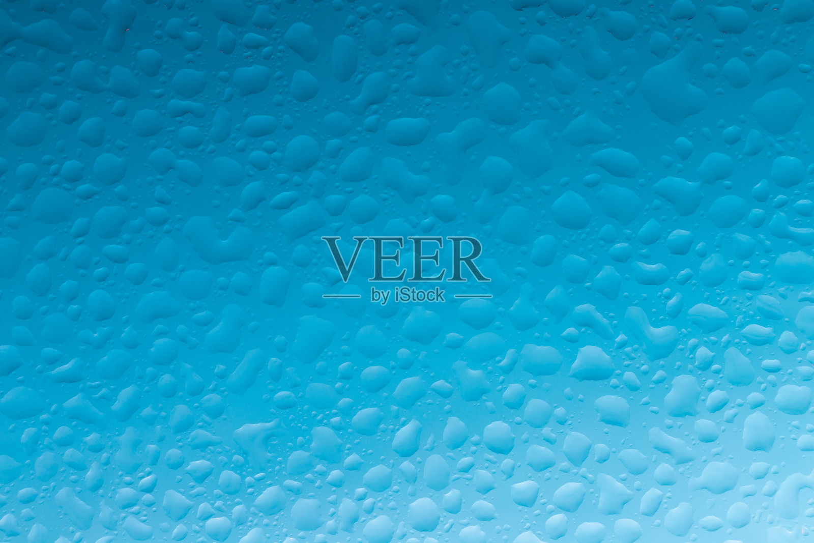 水滴在透明的玻璃上,玻璃是蓝色的,看起来很清新。照片摄影图片