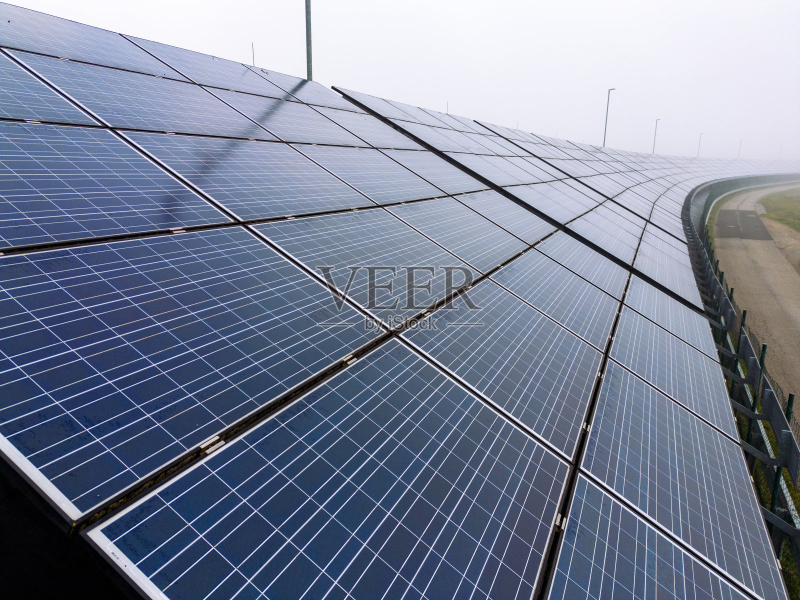 晴朗的天空下,乡村公路旁一排排的太阳能电池板照片摄影图片