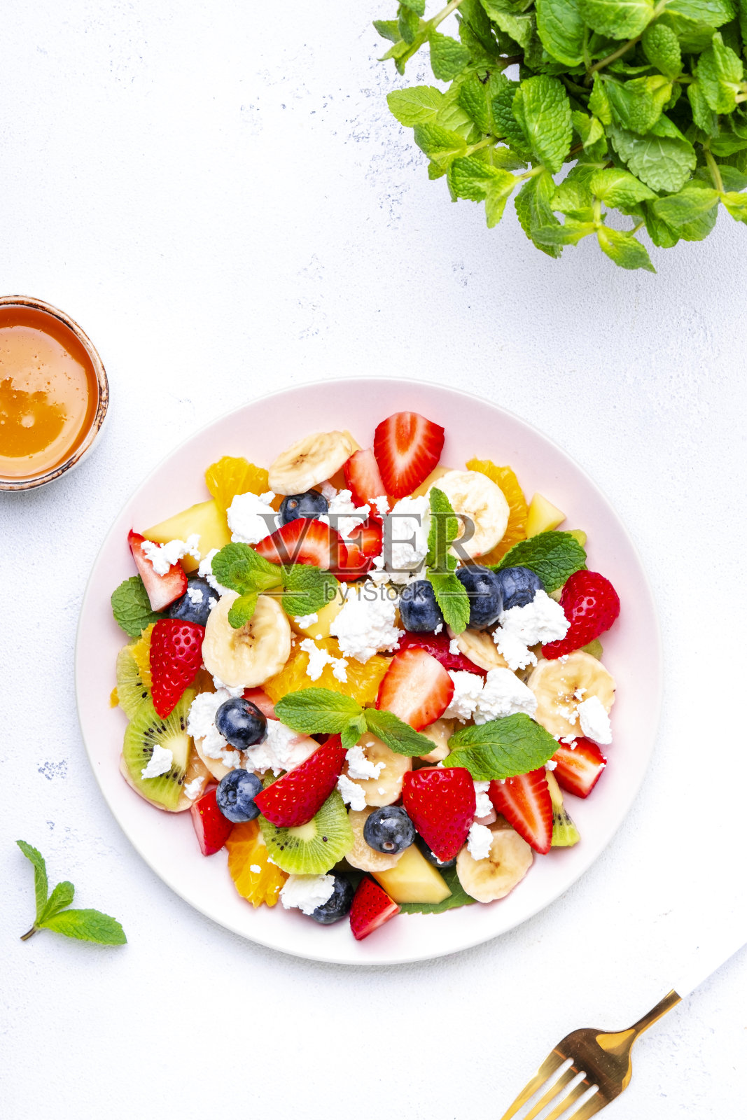 夏季水果和浆果沙拉,以新鲜草莓,蓝莓,香蕉,白干酪和薄荷为背景,俯视图照片摄影图片
