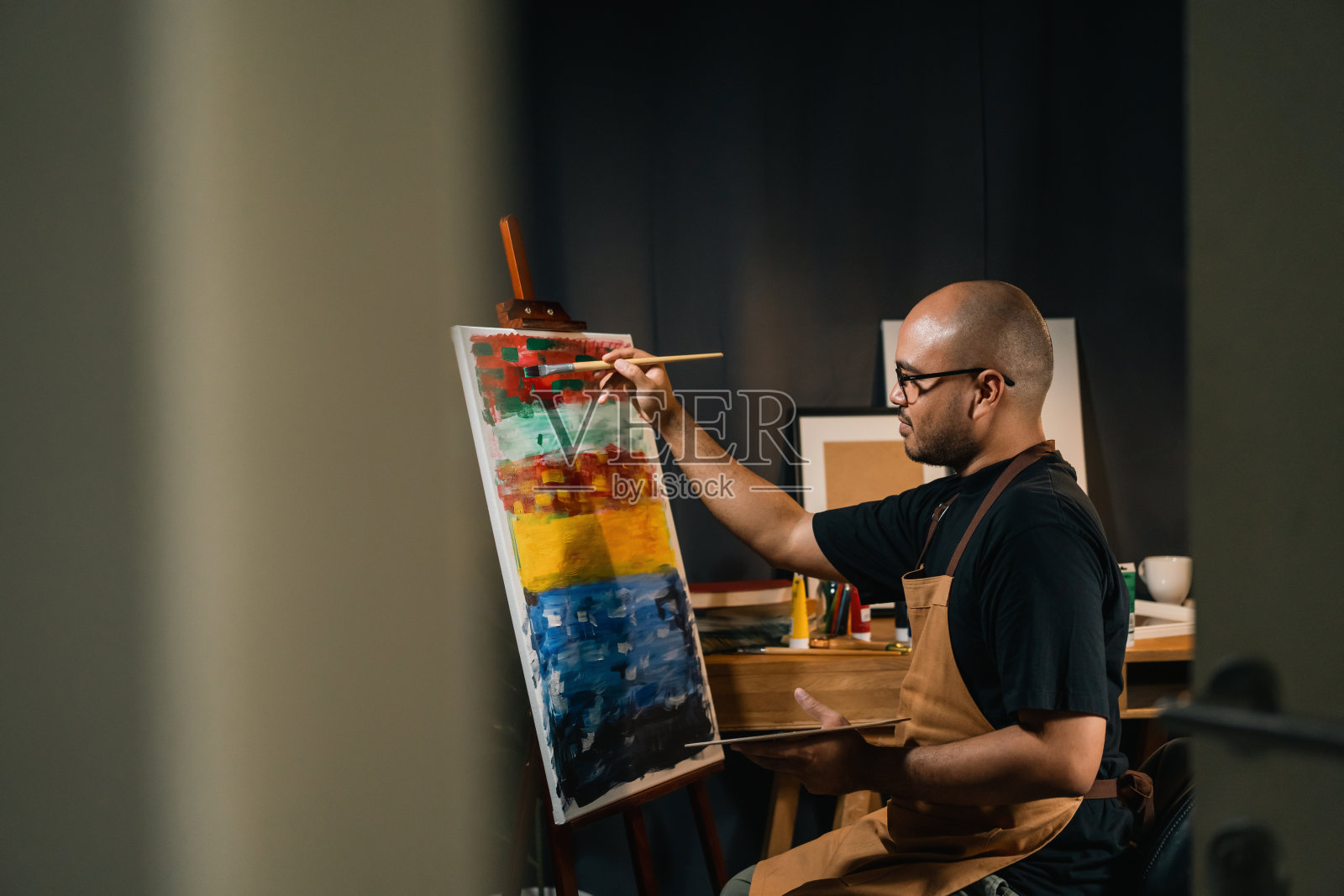 亚洲男子在暗房暖光艺术家工作的绘画与刷子和不同的丙烯酸颜料。作为艺术概念的男艺术家在创意工作室的画布上作画照片摄影图片