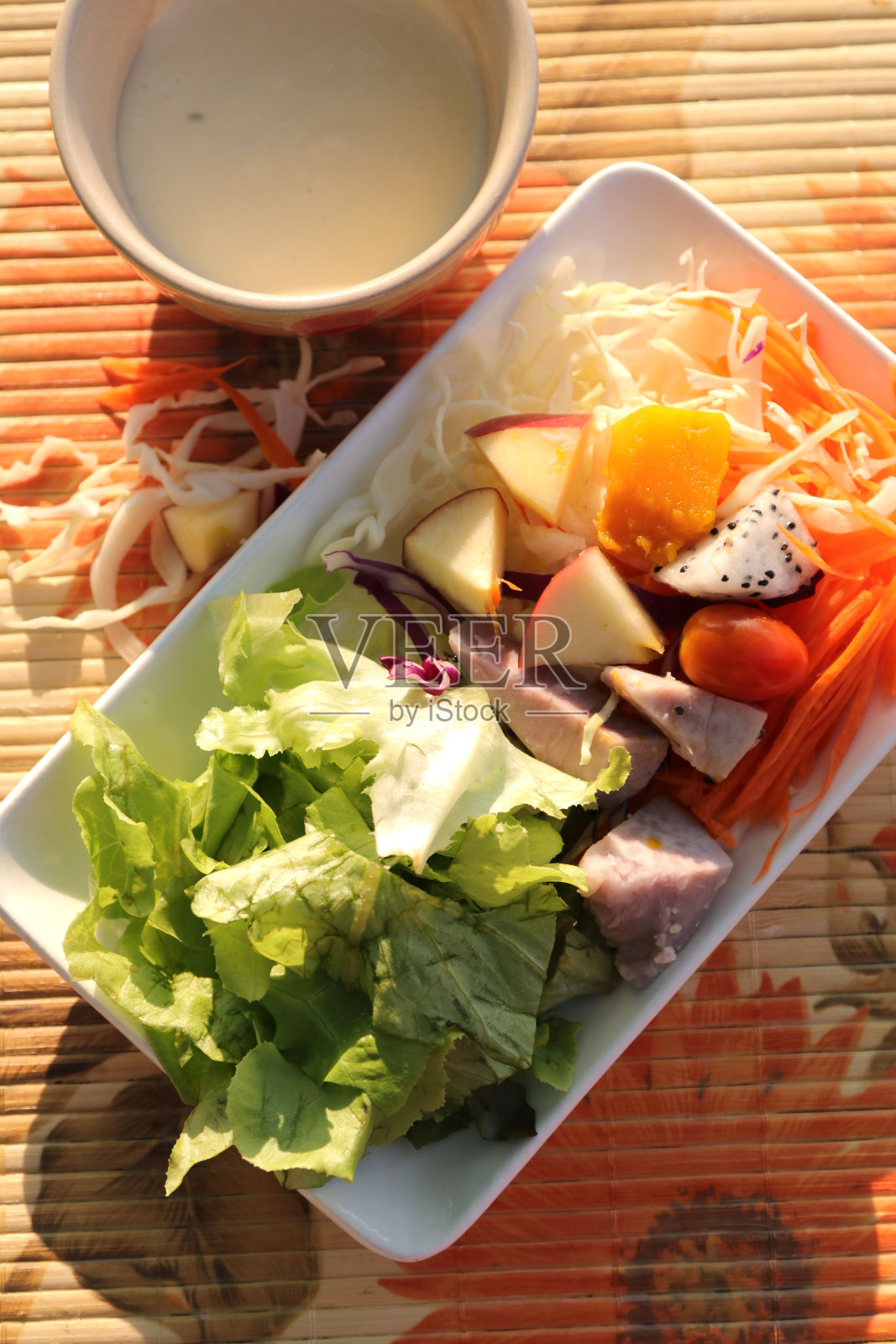 新鲜菜肴中混合的水果和蔬菜沙拉是健康的一餐,加上温暖的早晨阳光,更增添了开胃的气氛。照片摄影图片