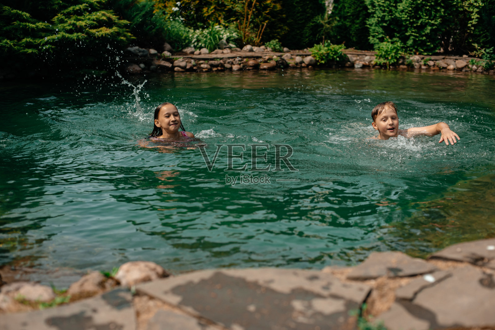 孩子们在池塘里游泳。照片摄影图片