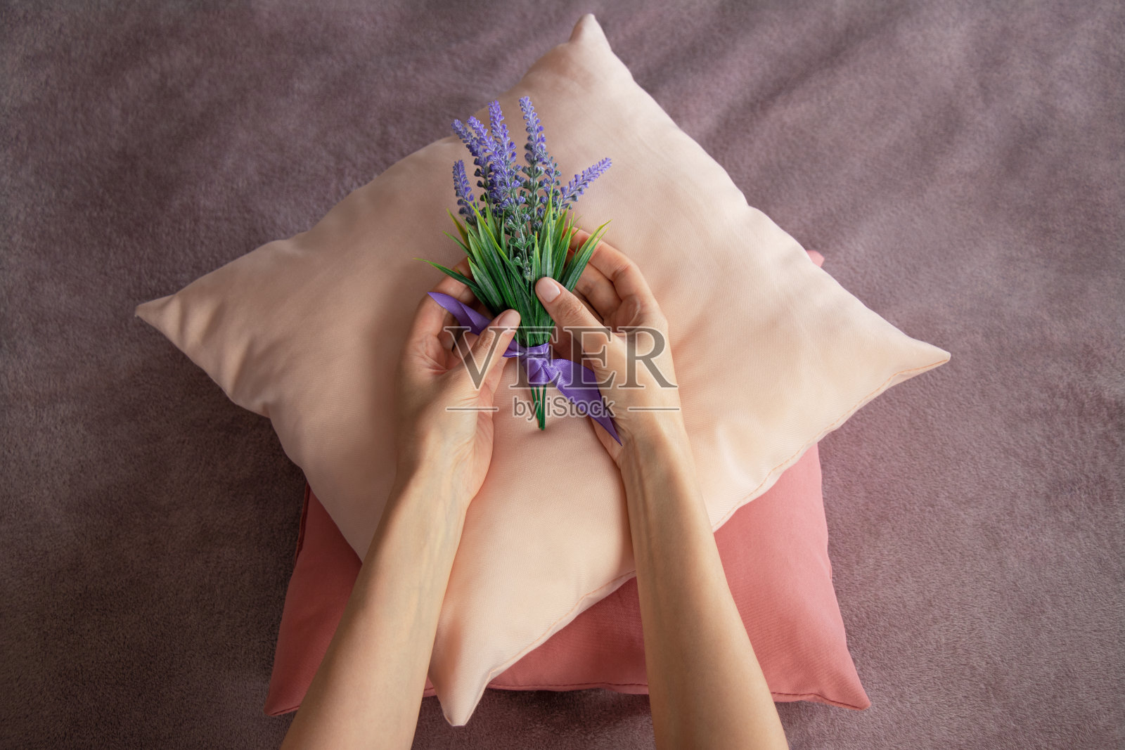俯视图女性的手把一束薰衣草放在彩色枕头上。专业服务员用鲜花装饰床,为客人准备房间照片摄影图片