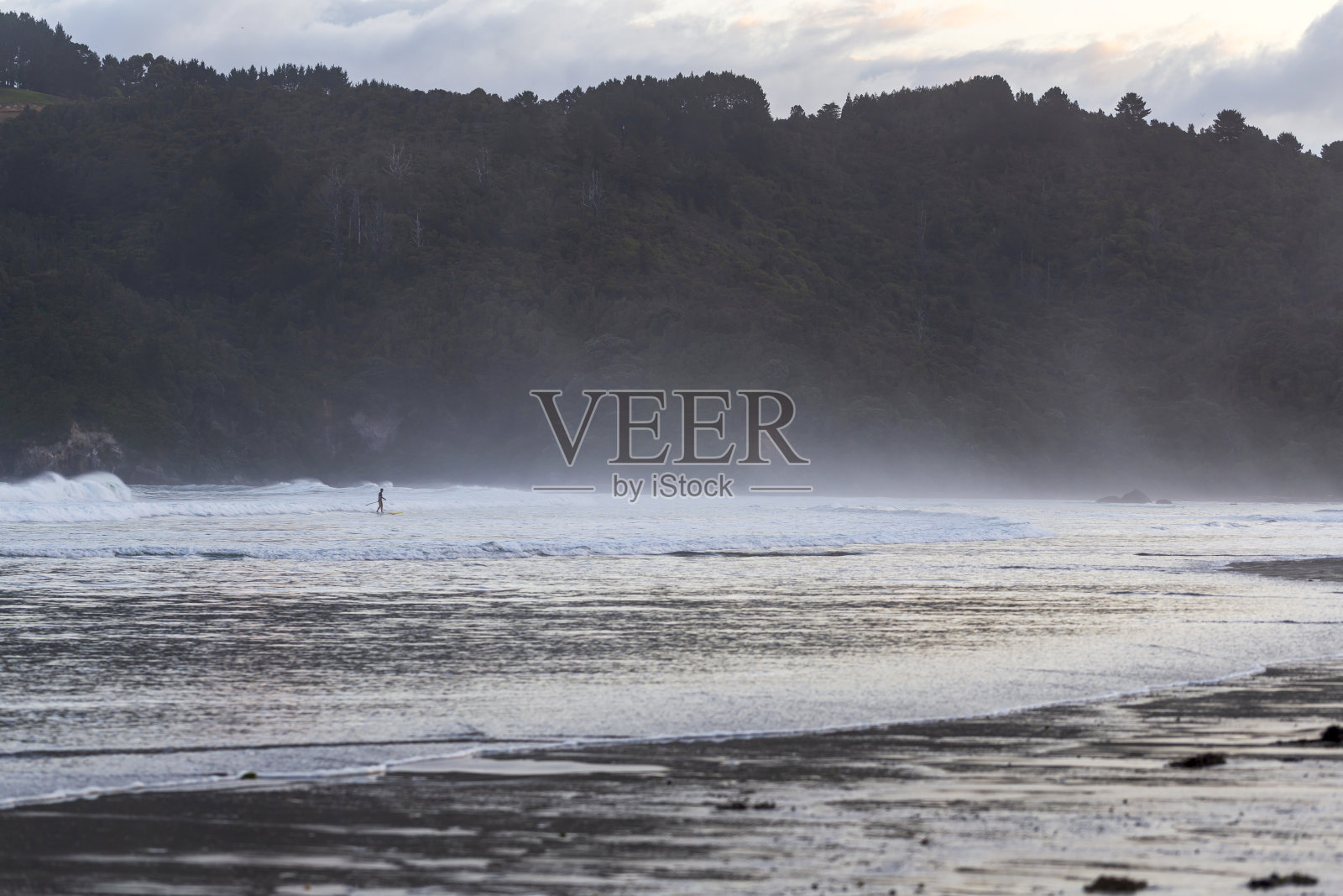 一名男子在旺加马塔海滩用桨板冲浪照片摄影图片