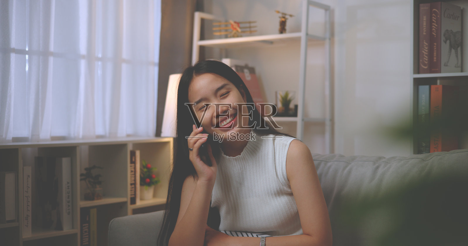 年轻的亚洲女子在客厅用智能手机快乐地聊天照片摄影图片