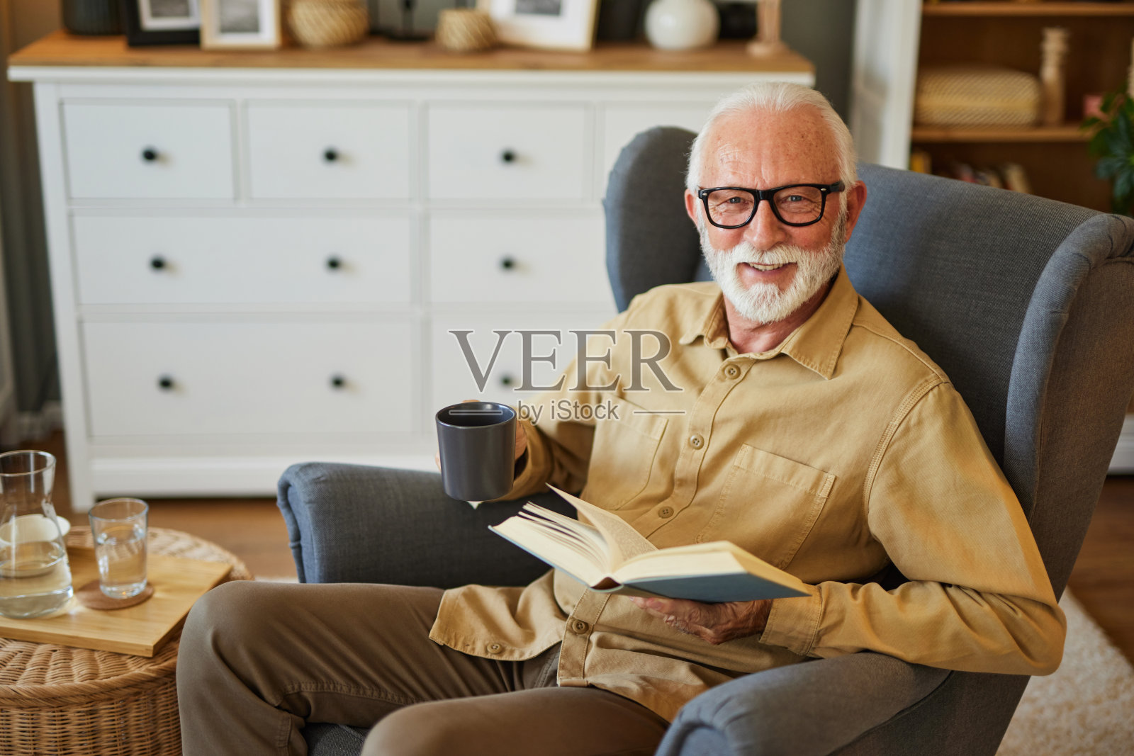 老人坐在家里的扶手椅上看书照片摄影图片