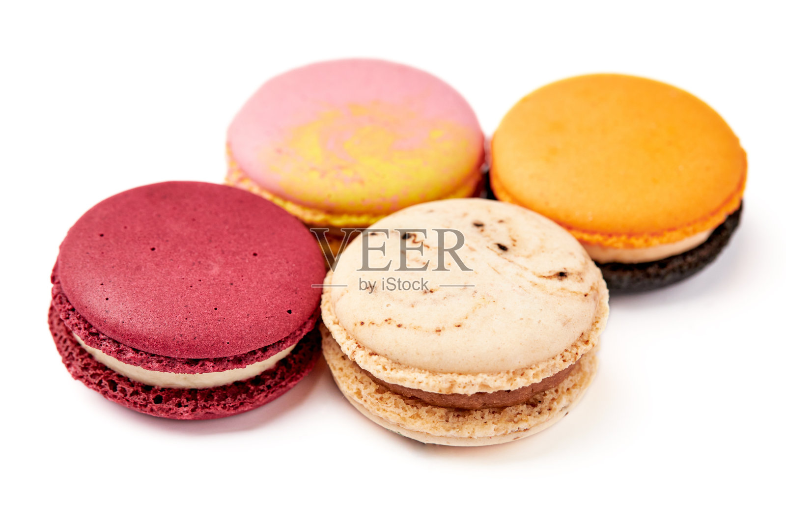 4个彩色马卡龙(粉色、红色、橙色和奶棕色)的特写,它们被隔离在白色的背景上。照片摄影图片