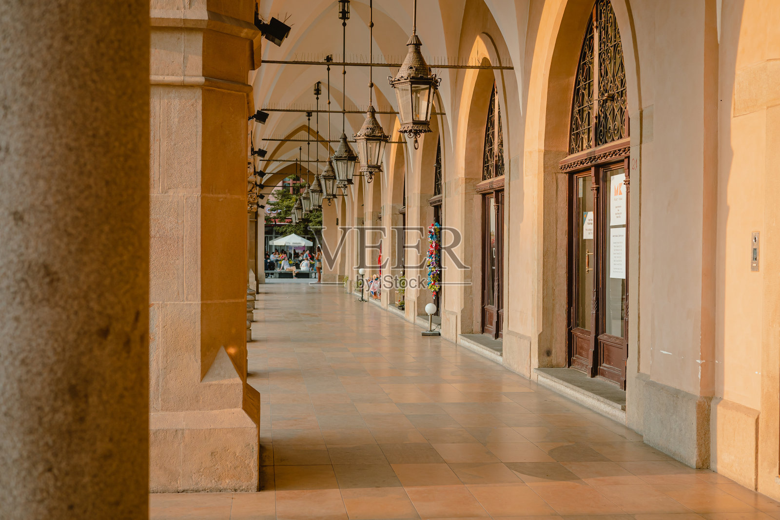 夏日,克拉科夫主广场或Glavny Rynek上的拱廊。可见的椅子和鲜花在拱门的末端。没有人步行,游客免费。照片摄影图片