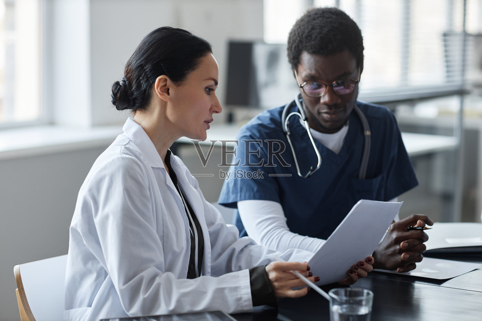 自信的女临床医生向年轻的助理展示医疗文件照片摄影图片