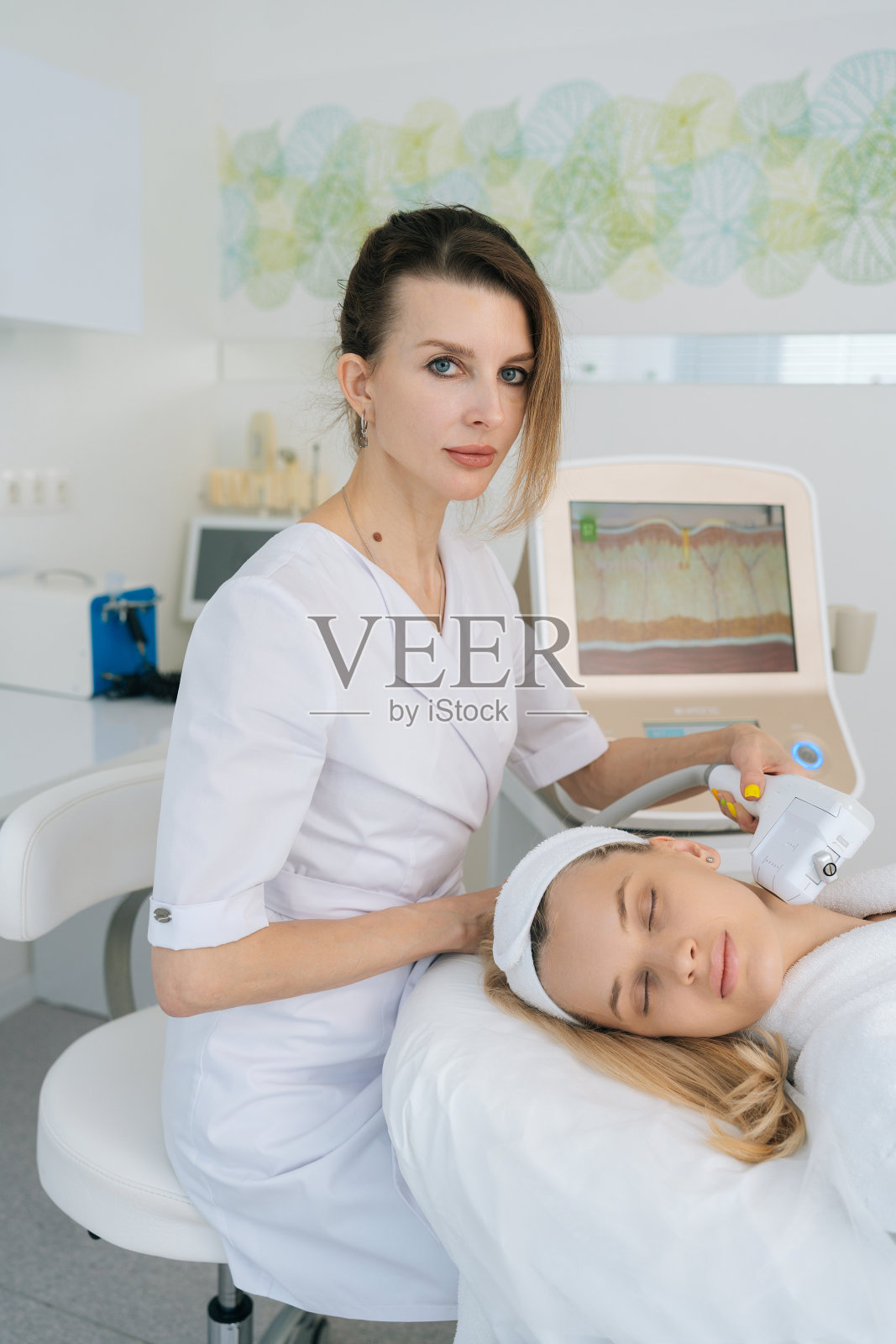 在现代美容诊所,美容师医生使用激光机器和超声波SMAS提升皮肤,使皮肤恢复活力。照片摄影图片