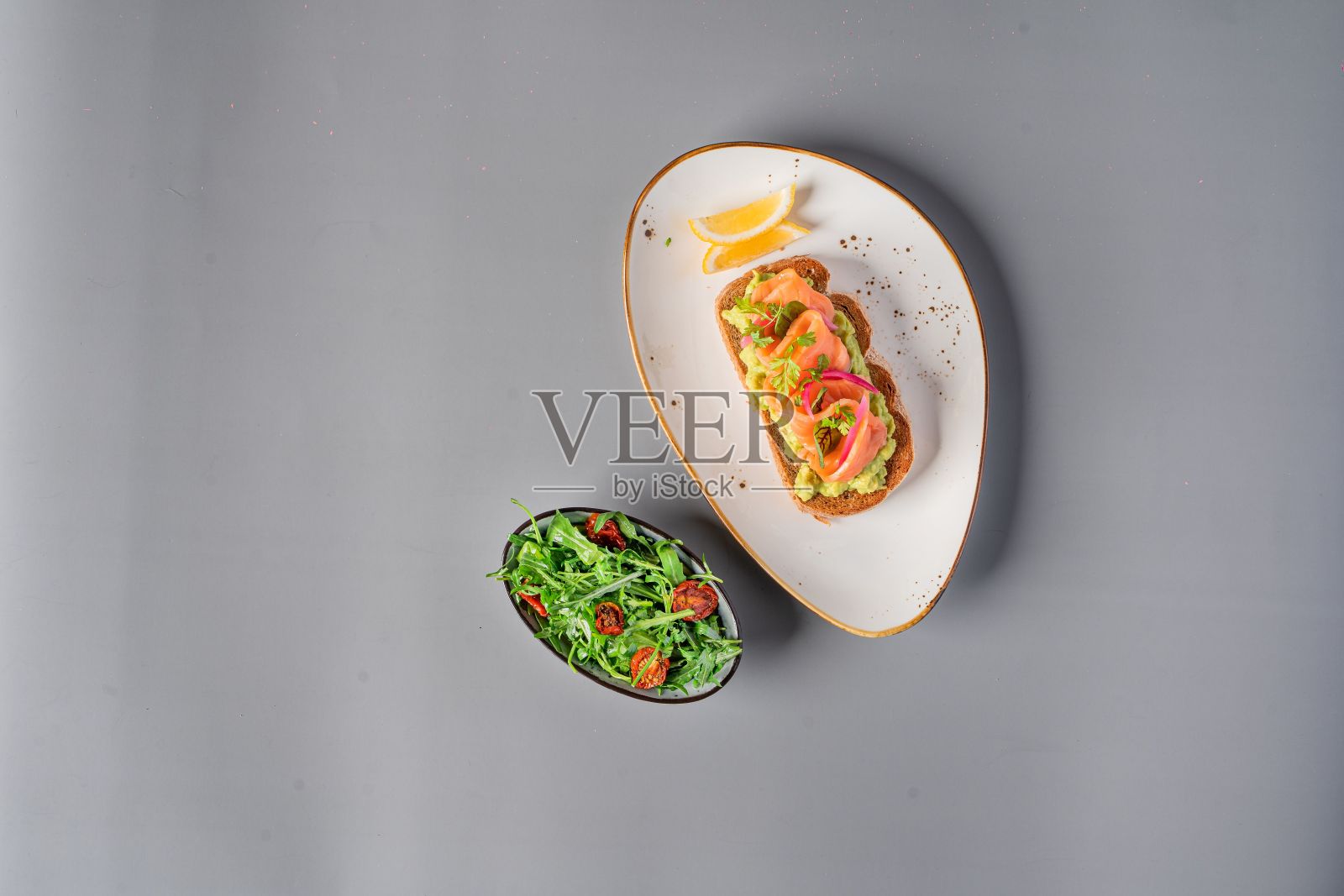 灰色背景上鲑鱼三明治和沙拉的俯视图照片摄影图片