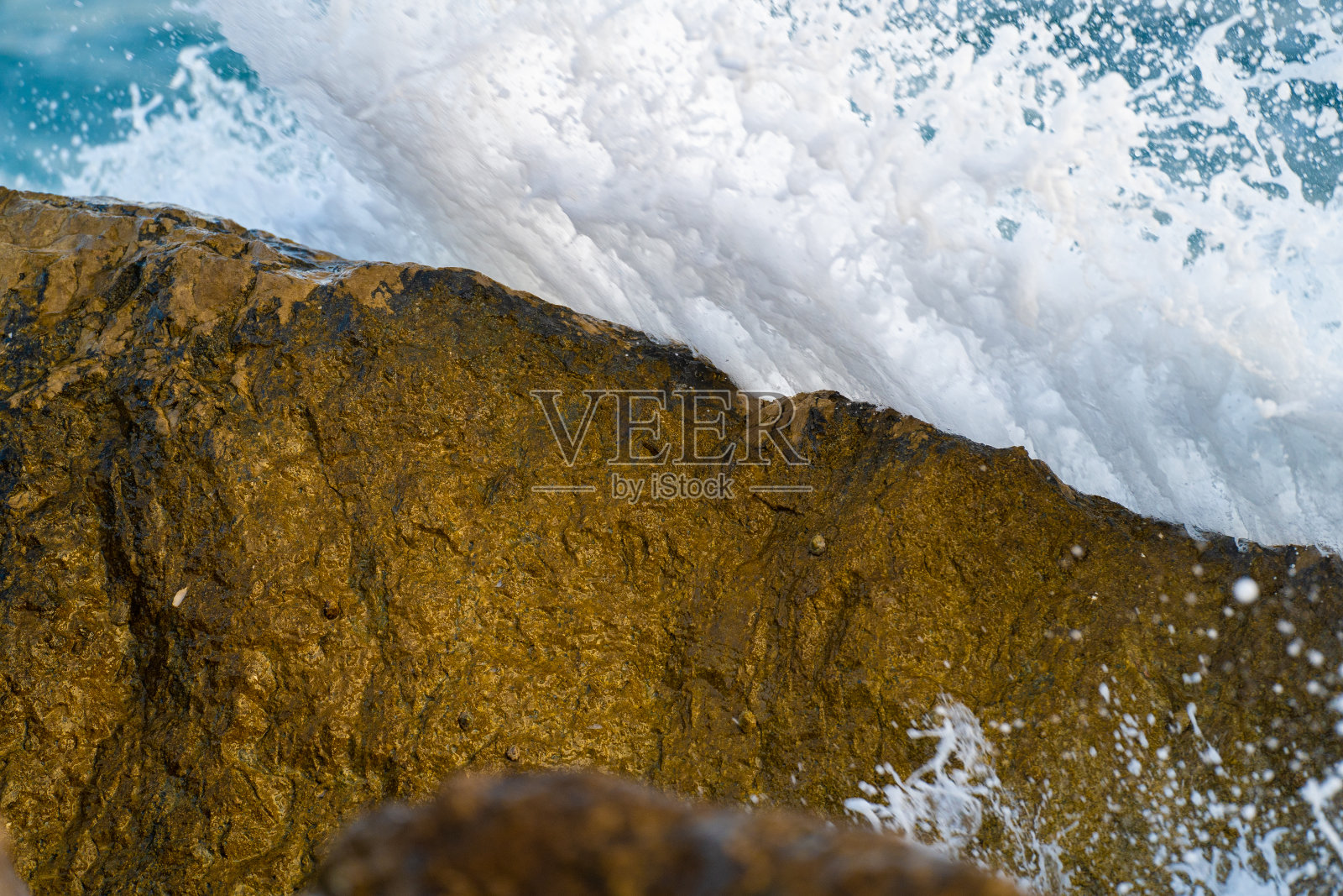 海浪和泡沫冲击着海边的岩石。照片摄影图片