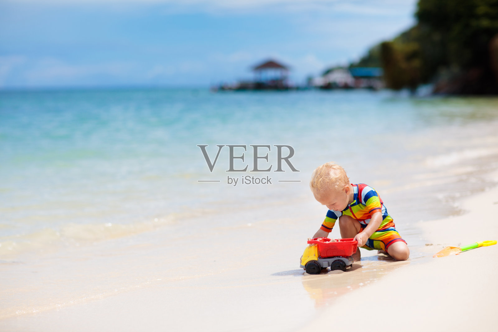 孩子们在热带海滩上玩耍。沙子和水的玩具。照片摄影图片