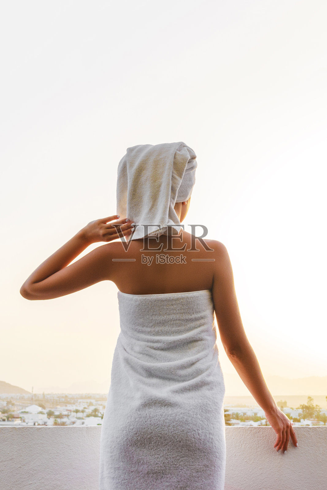 这个女孩站在阳台上看山上的日落照片摄影图片