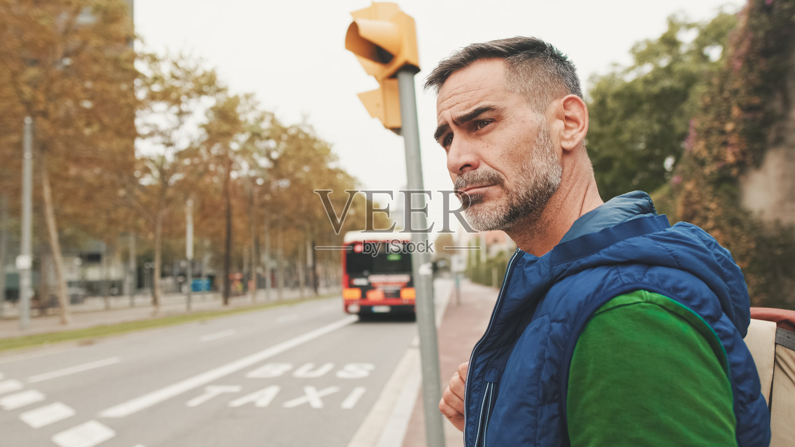 成熟的男子游客穿着休闲服,肩上背着背包,站在人行横道上环顾四周照片摄影图片