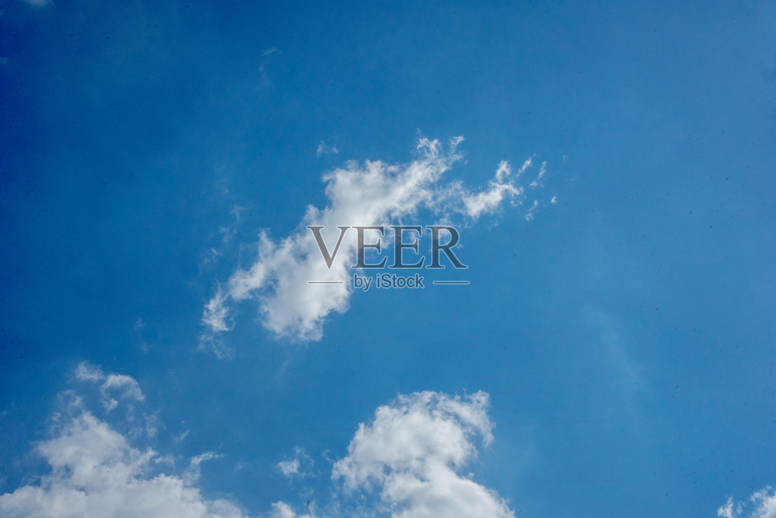 白云在晴朗的蓝天中央,在炎热晴朗的下午照片摄影图片