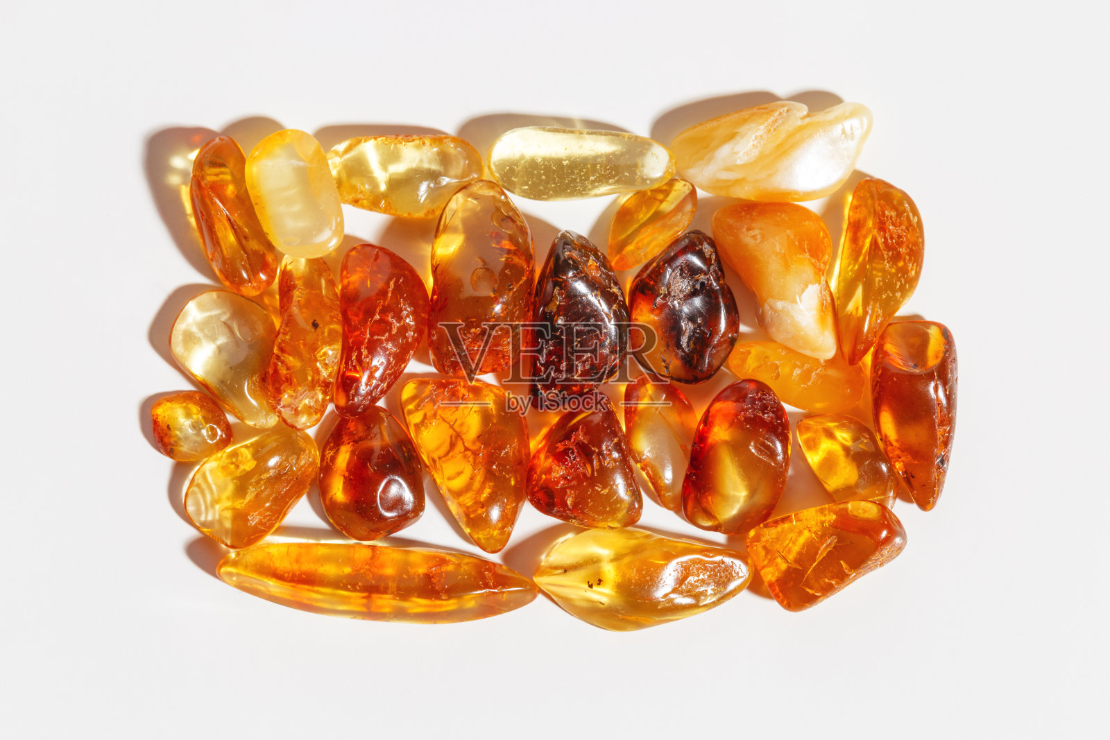 天然宝石琥珀石在阳光下,黄橙色渐变色孤立白色背景。天然的矿物。审美生活方式琥珀宝石,平面图案,片古树脂照片摄影图片