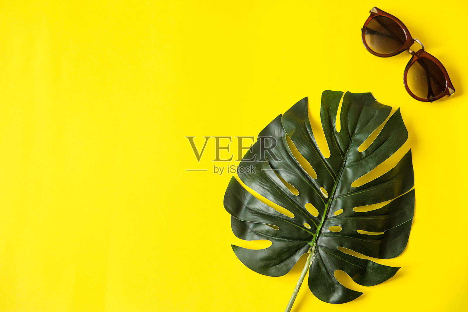 夏天即将来临的概念。黄色背景下的热带树叶和太阳镜。夏天平躺,俯视图。空间的文本。照片摄影图片