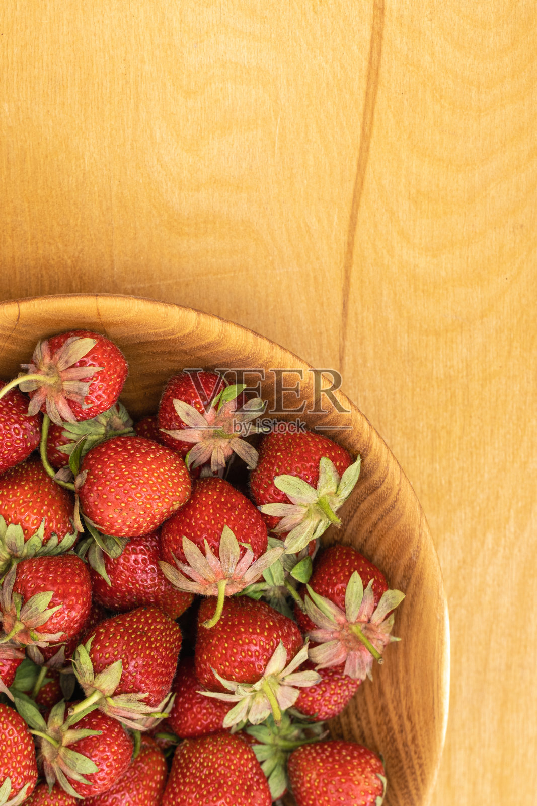 木碗里装满了刚摘下来的成熟的红草莓。夏季浆果富含维生素。健康营养理念。前视图。平躺照片摄影图片