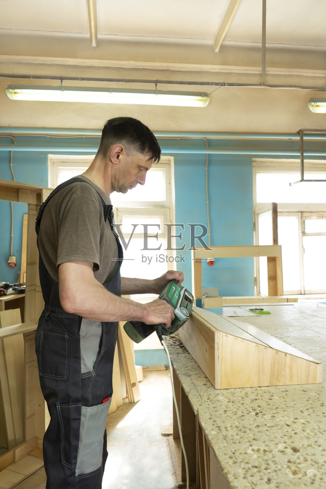 拥有木材磨床的专业木匠。家具制造。照片摄影图片