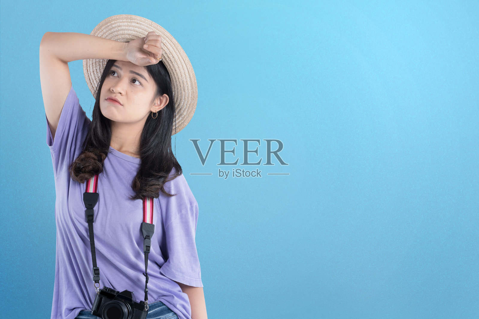 一名亚洲妇女戴着帽子,站着相机,脸上带着不高兴的表情照片摄影图片