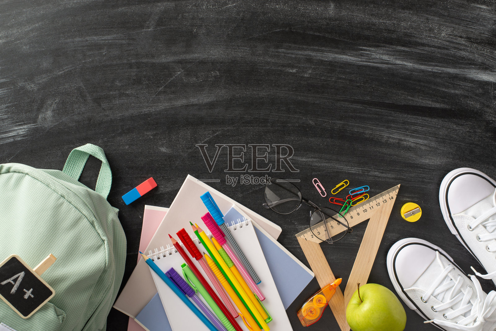 Education-themed显示。高角度拍摄一个背包,运动鞋,以及黑板表面上的各种学习材料,文字或宣传内容的复制空间照片摄影图片