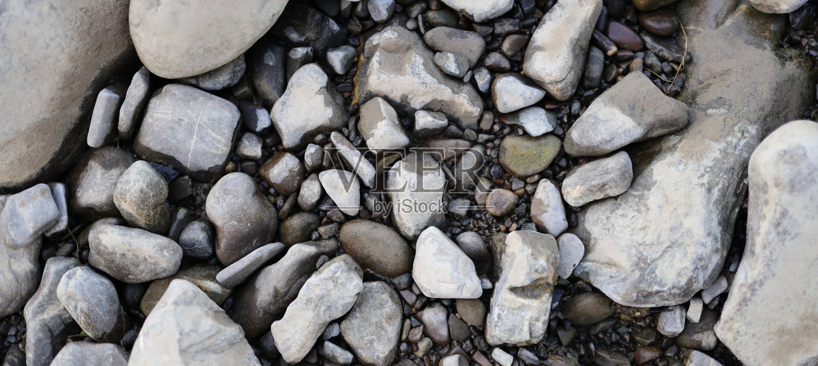 收集岩石和鹅卵石。这些岩石有不同的大小、形状和颜色。颜色从白色到灰色到棕色不等。照片摄影图片