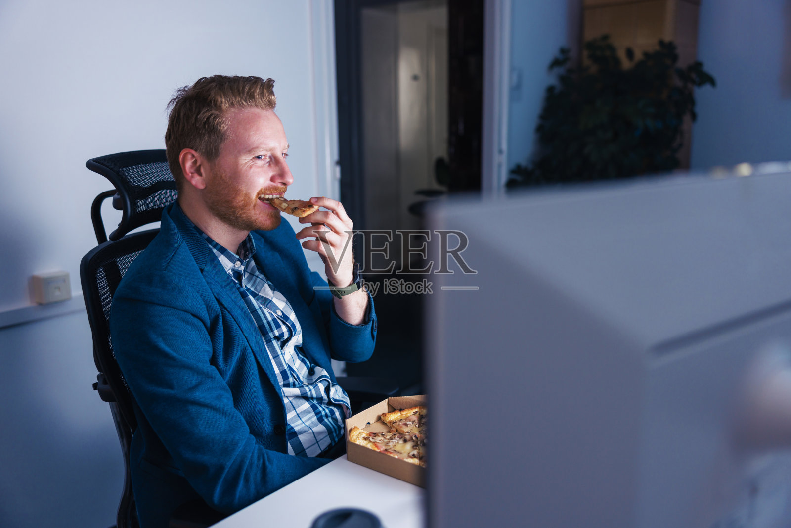 在办公室工作到很晚的商人吃着披萨喝着咖啡照片摄影图片