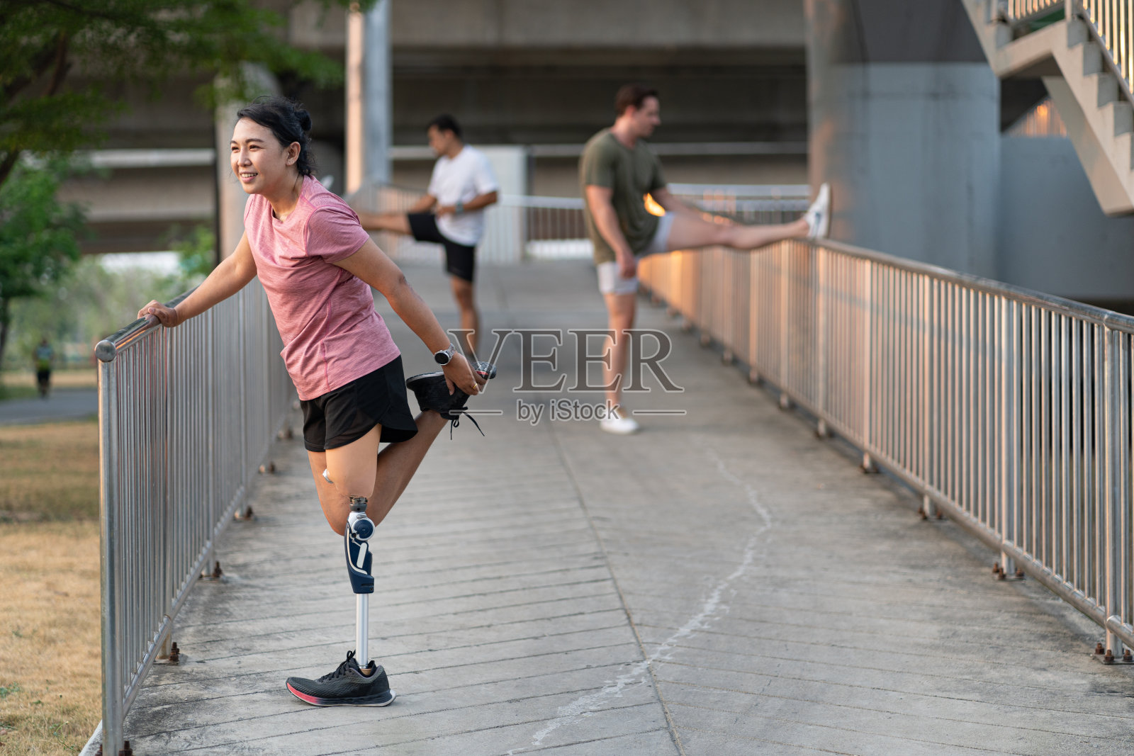 快乐运动亚洲妇女与假腿和朋友伸展在公园城市照片摄影图片
