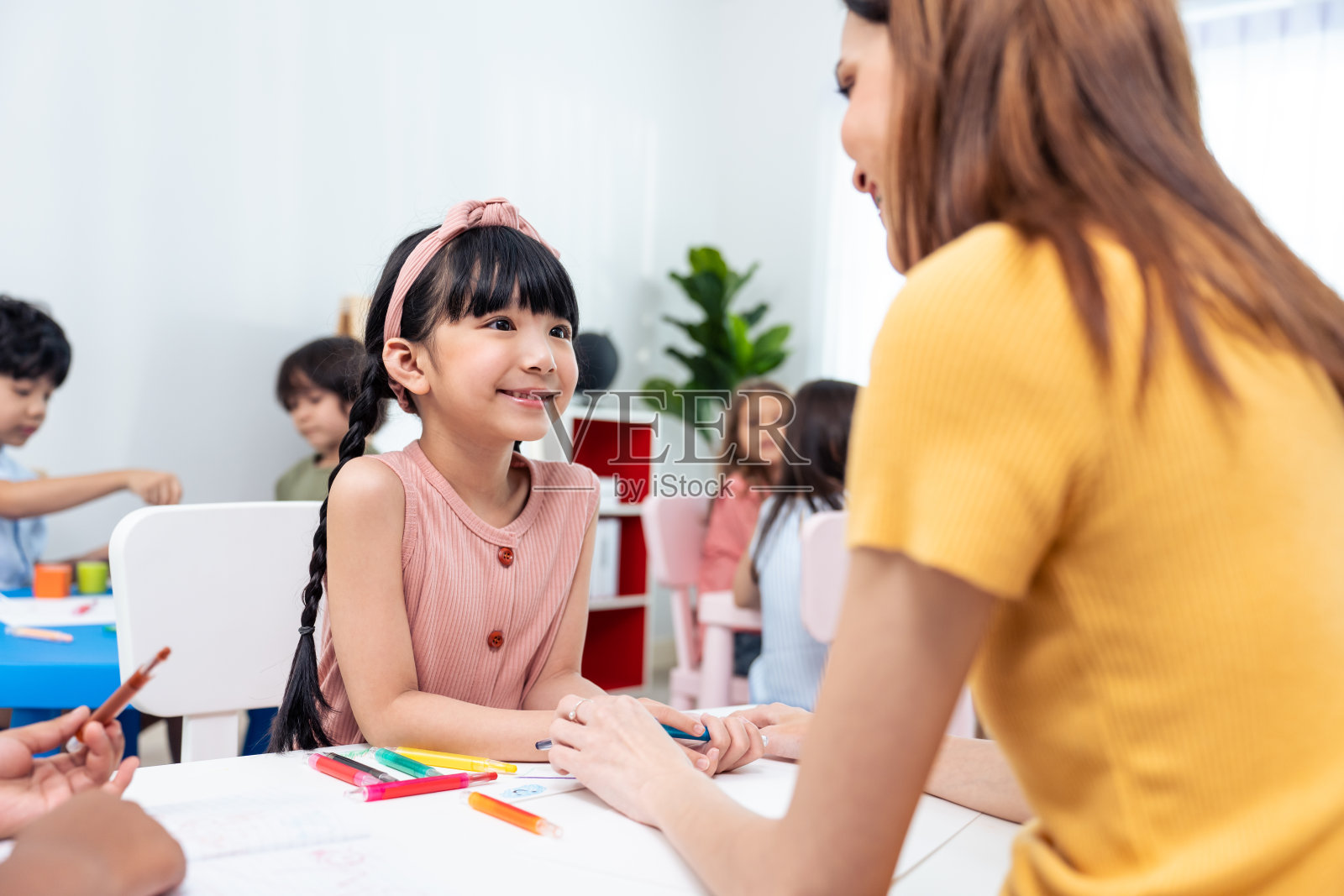 白种漂亮的年轻女性老师在学校教孩子们艺术。魅力教师女老师在幼儿园学前课堂上与学生讲解教育绘画。照片摄影图片