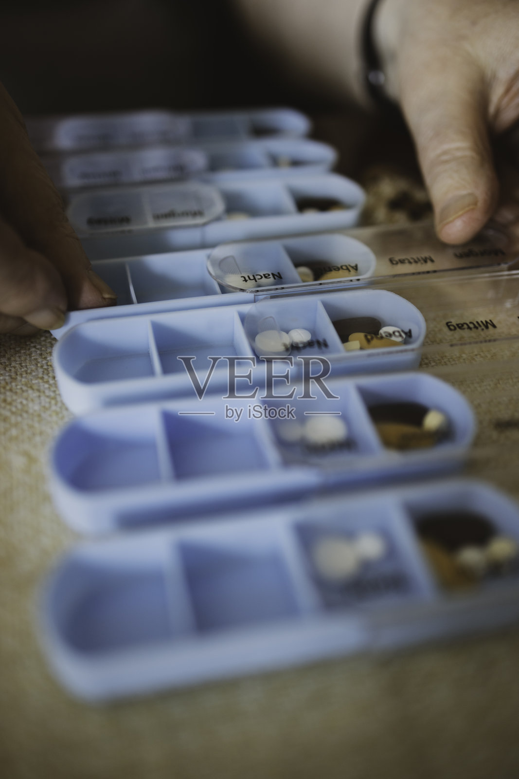 一位老人正在把药片和胶囊放进一个7天药片收纳盒里照片摄影图片