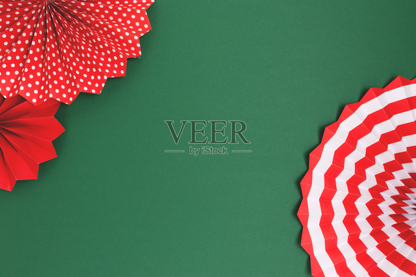 由绿色背景的红色纸扇制成的框架。照片摄影图片