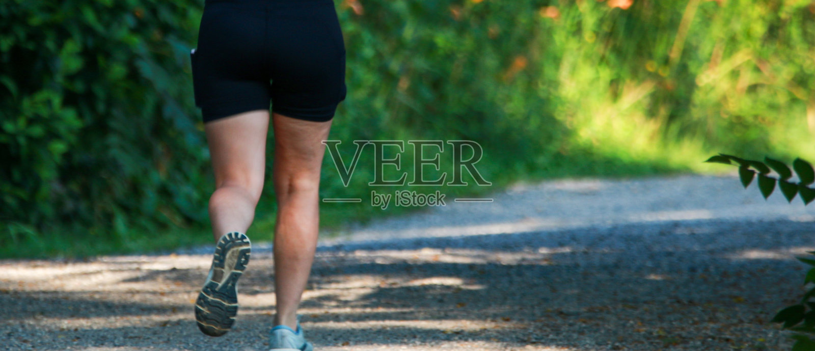 一个女人在树林里一条土路的阴凉处奔跑照片摄影图片