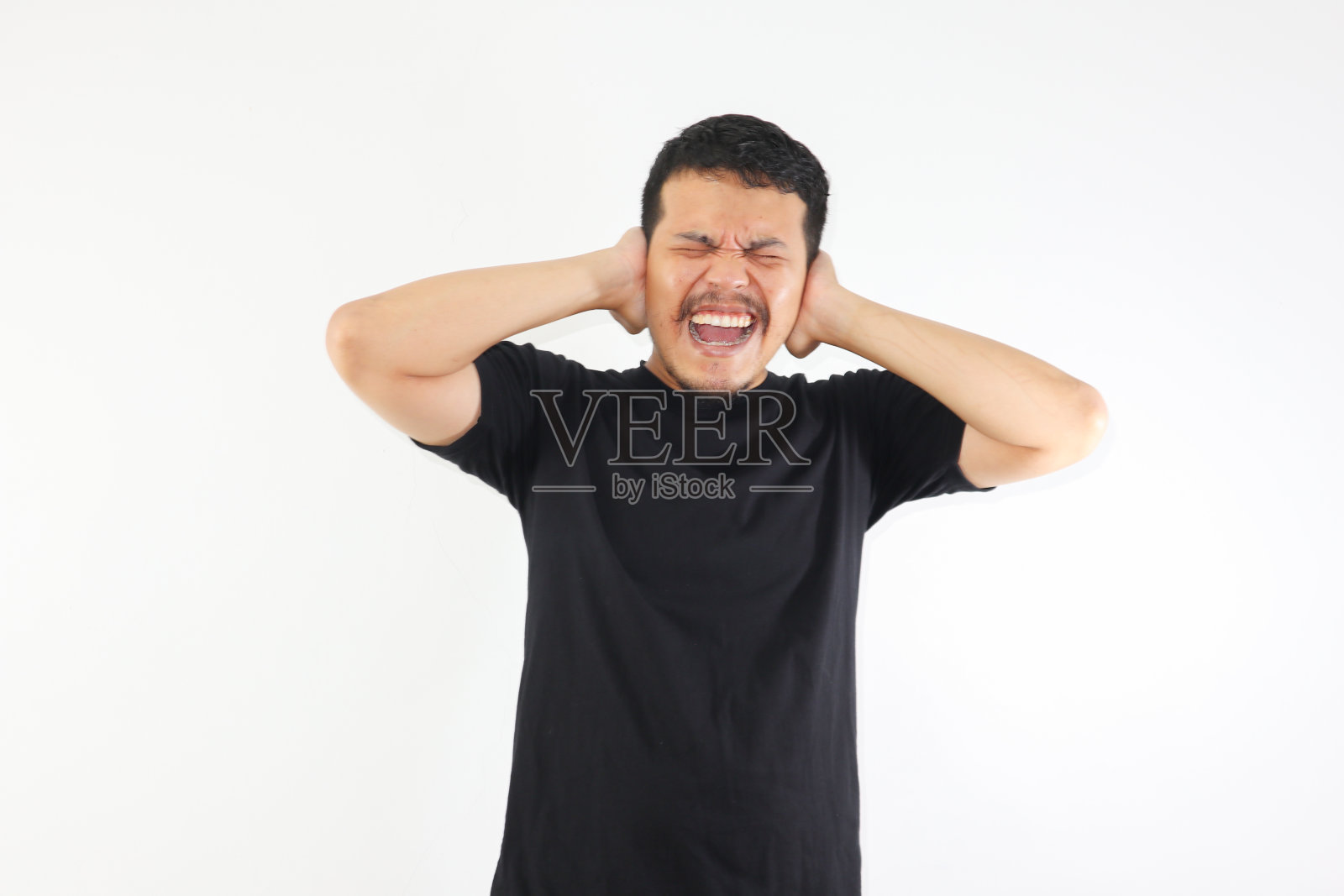成年亚洲男子尖叫绝望,而用手关闭他的耳朵照片摄影图片