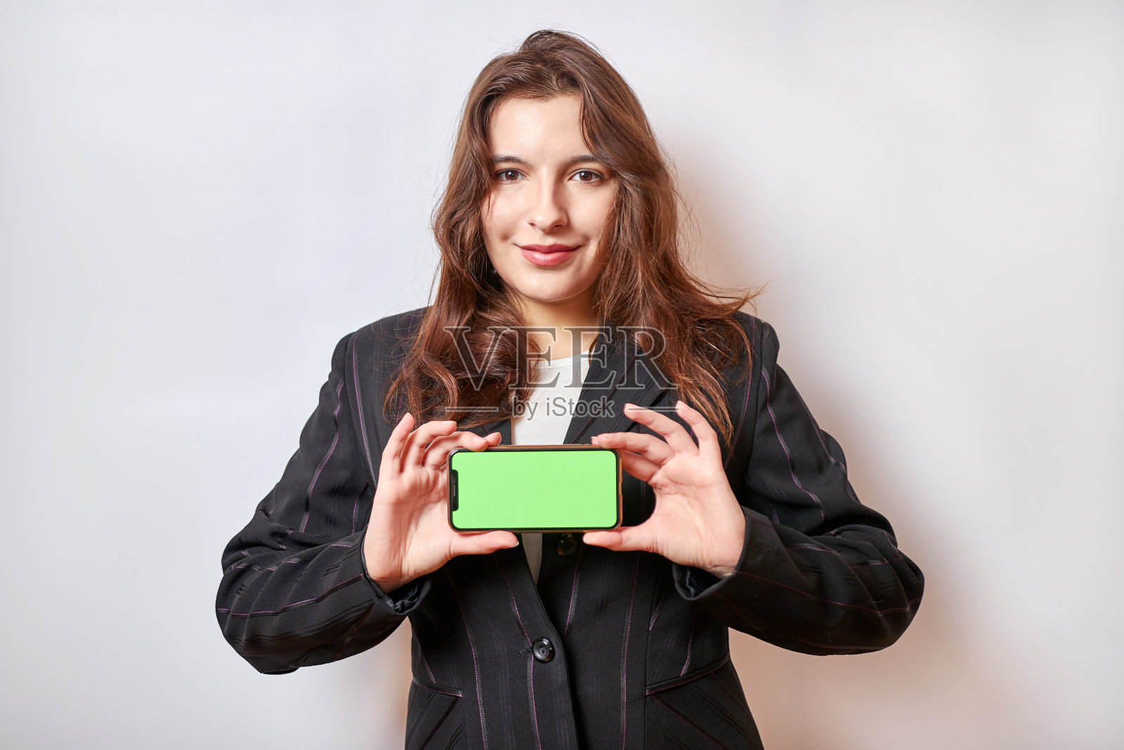 漂亮女孩拿着绿色屏幕的智能手机。照片摄影图片