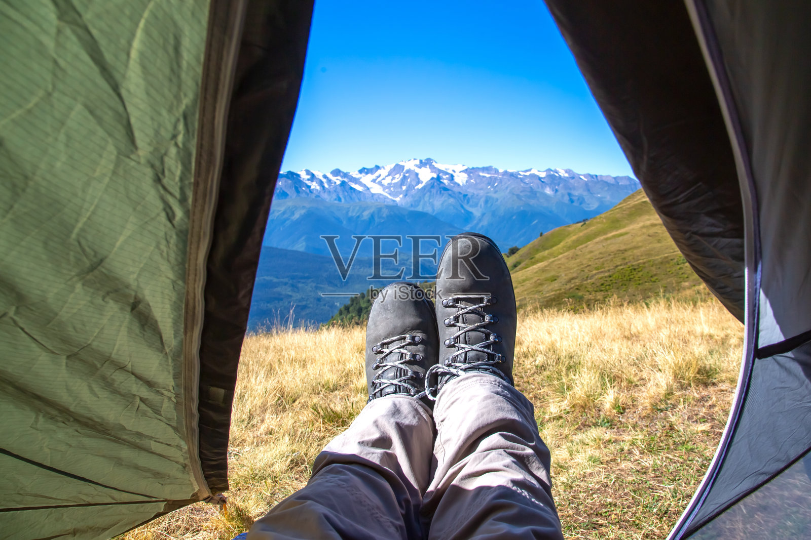 脚上穿着靴子的游客走出帐篷,背景是山脉照片摄影图片