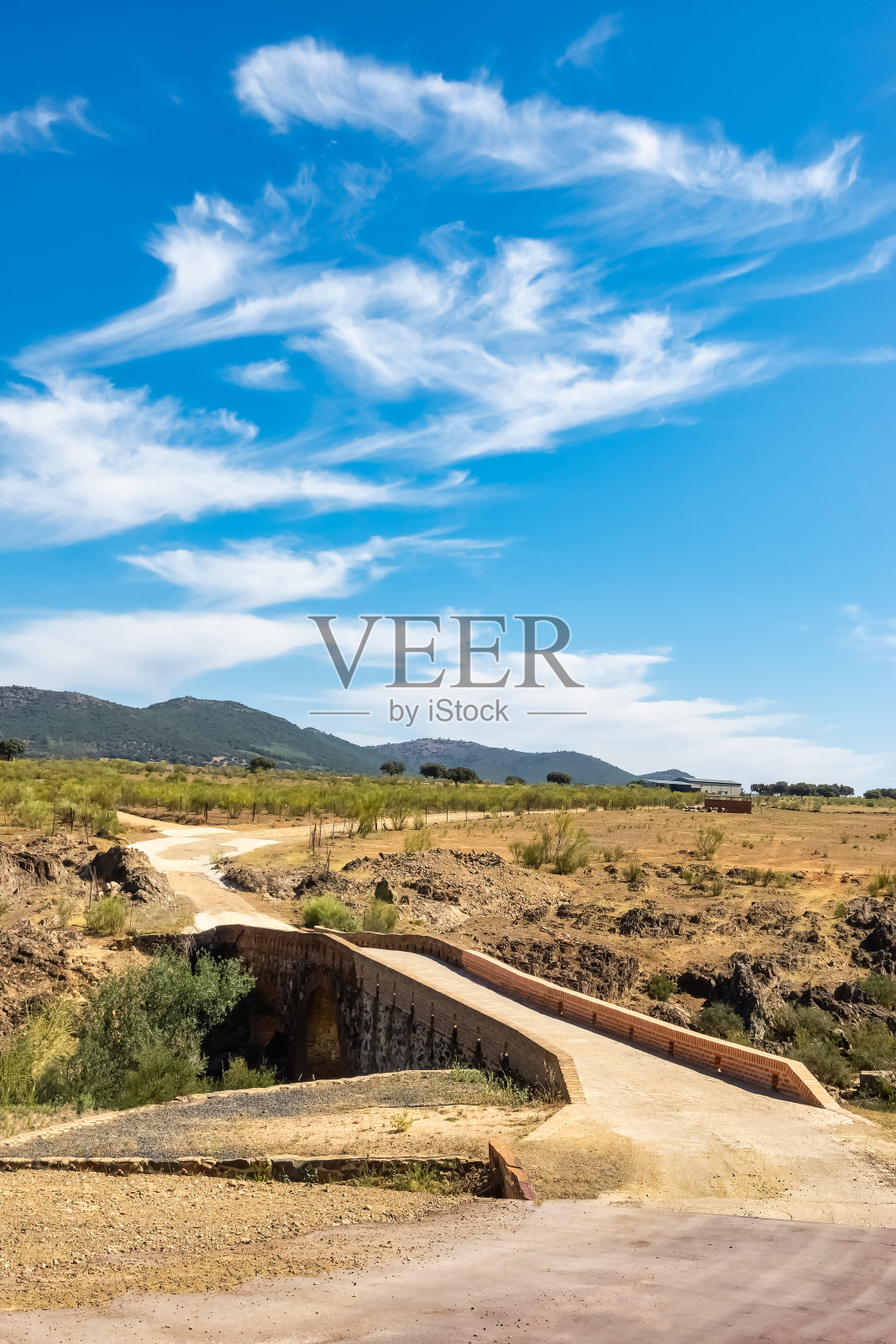 罗马石桥,横跨一条小溪,通往附近山脉的山顶,阿古多,雷亚尔城。照片摄影图片